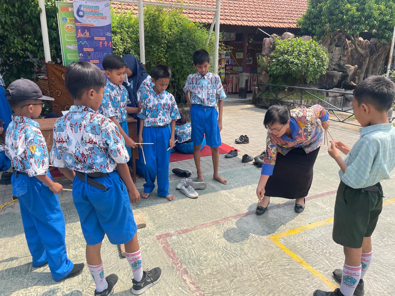 Ibu Kepala Sekolah memeragakan permainan "Patil Lele"